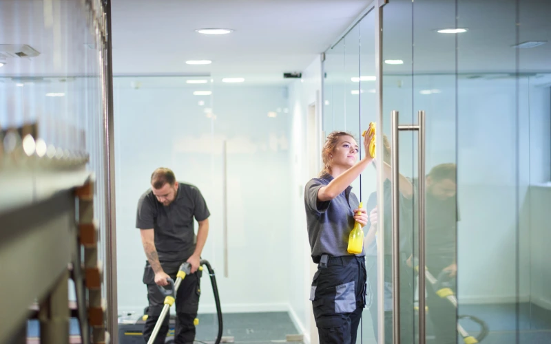 a women cleaning the glass and men holding the machine and doing deep cleaning 
