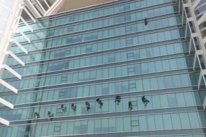 a group of people cleaning the exterior of high raise building