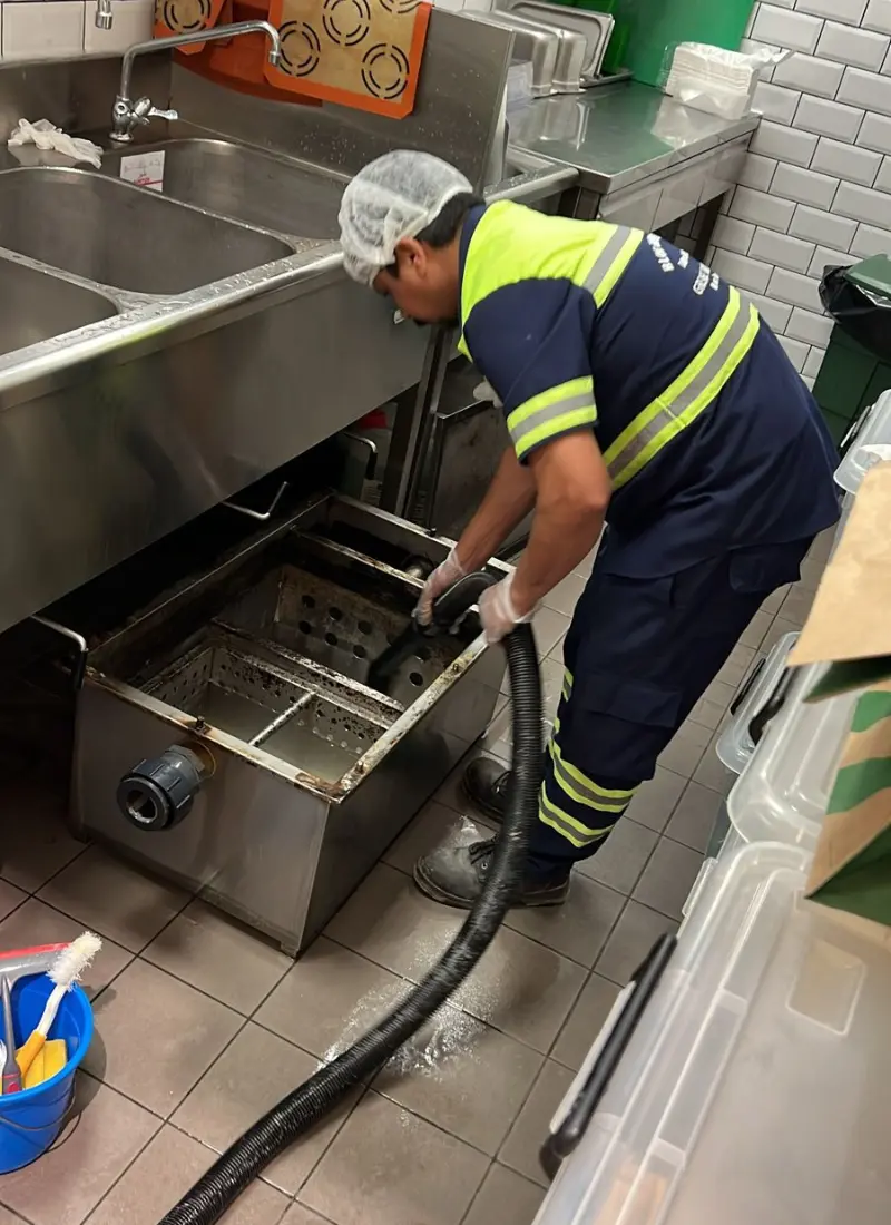 A cleaner removing the slude from the Grease trap box with sucking machine